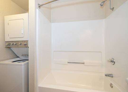 A white bathroom with a tub, toilet, and washing machine.