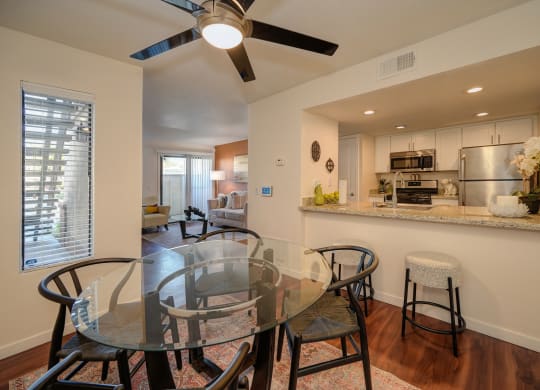 Model home dining area with ceiling fan. Open floor plan feel since you can view kitchen and living room from the dinning area. Dining table is set for four at Rocklin Manor  Apartments, Rocklin  