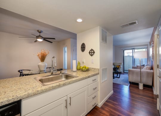 Model kitchen with hard wood inspired flooring, white counters, ceiling fan in dining area and views of the living room at Rocklin Manor  Apartments, Rocklin  , CA