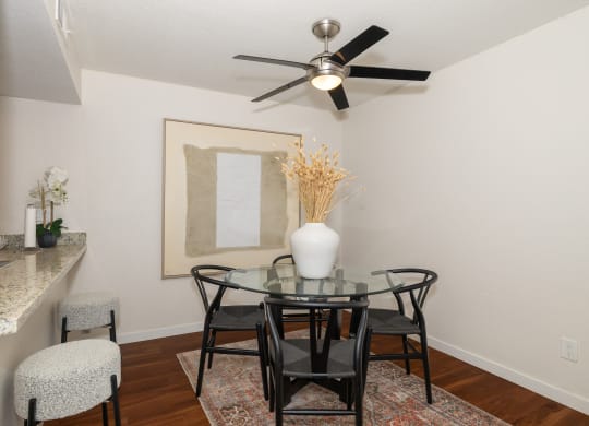a dining room with a glass table and chairs and a ceiling fan at Rocklin Manor  Apartments, Rocklin  