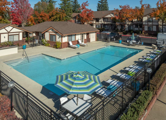 a swimming pool with umbrellas and lounge chairs around it at Rocklin Manor  Apartments, Rocklin  ,California, 95677