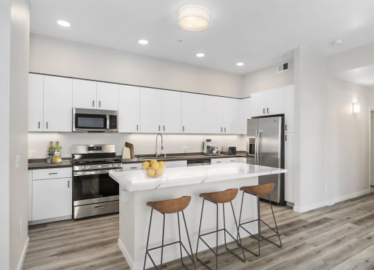 a kitchen with white cabinetry and a large white island with three stools