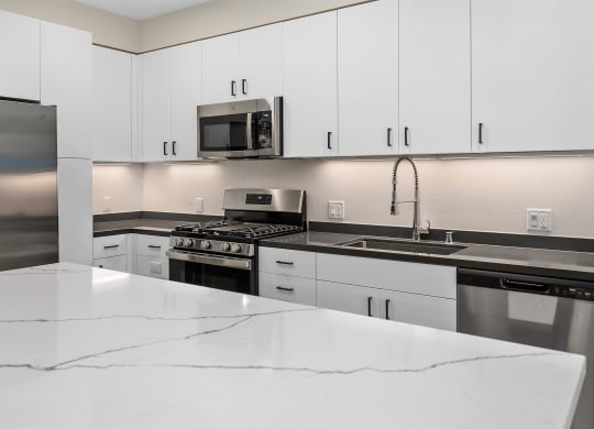 an all white kitchen with stainless steel appliances and white counter tops