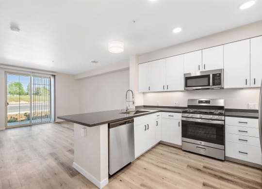 an empty kitchen with white cabinets and stainless steel appliances