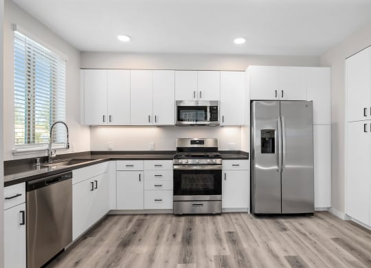 a kitchen with white cabinets and stainless steel appliances