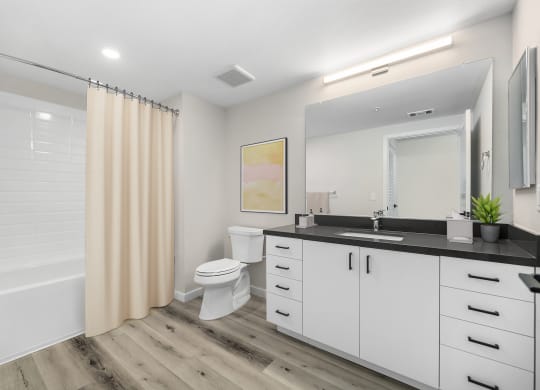 a bathroom with white cabinets and a black countertop