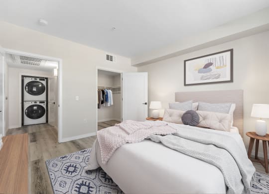 a bedroom with a bed and a closet with a washer and dryer