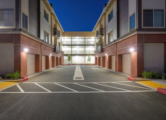 an empty parking lot in front of an apartment building at night