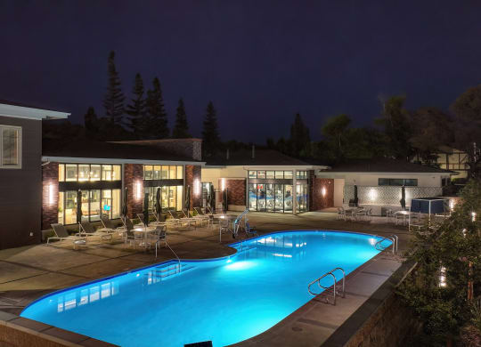 Community Swimming pool area at night with community clubhouse in the distance.