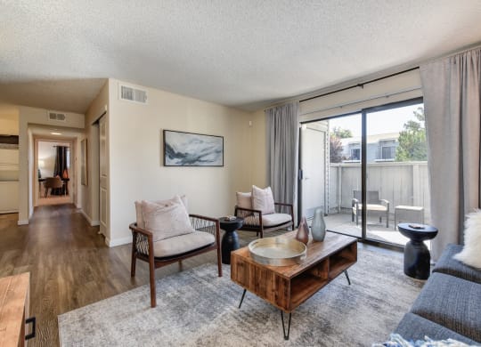 Living with Sliding Patio Doors,  Hardwood Inspired Floor, Gray/White Rug, Gray Sofa and Round Mirror at Silverstone Apartments, California, 95618