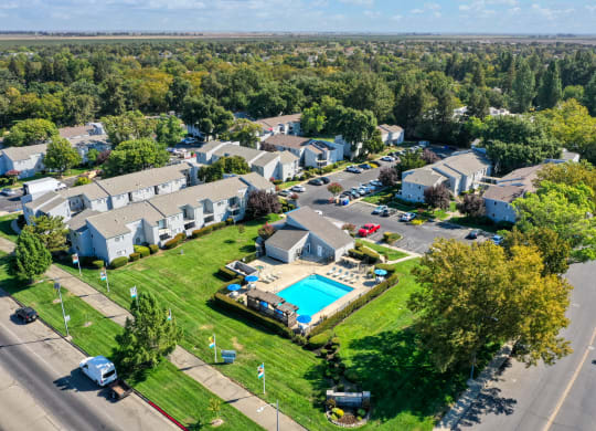 Drone photo overlooking the entire apartment community showcasing the pool, leasing office, mature landscaping and all of the apartment buildings. at Silverstone Apartments, Davis, California