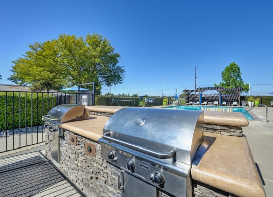 BBQ Picnic Area with Grills and View of Lounge Chairs and Pool at Silverstone Apartments, Davis, California