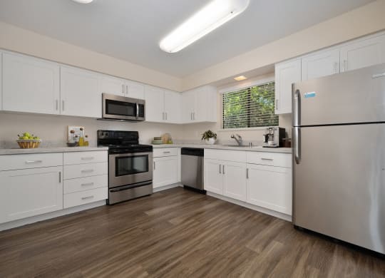 a kitchen with white cabinets and stainless steel appliances in the townhome floorplan at Silverstone Apartments, Davis, CA, 95618