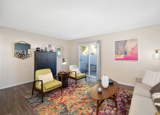 a living room with a couch and chairs and a door to a balcony