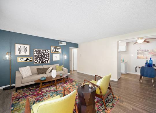 a living room with a couch and chairs and a dining room of in the distance