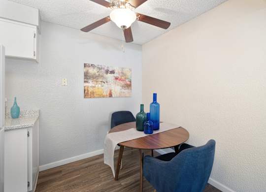 a dining room area with a table and chairs and a ceiling fan