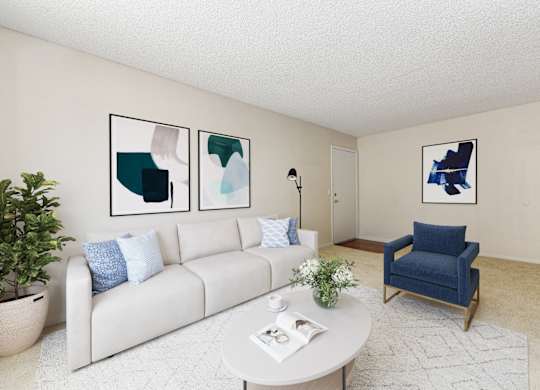 A living room with a white couch, a blue chair, and three framed pictures on the wall.