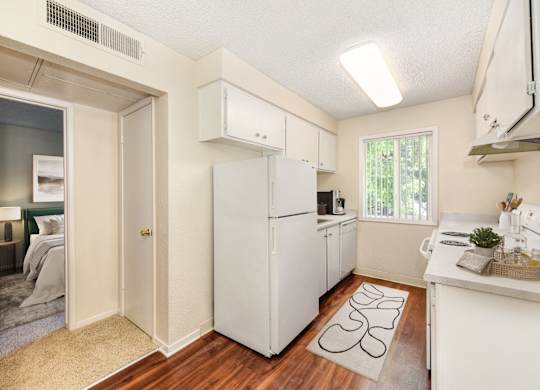 A small white kitchen with a refrigerator, sink, and cabinets.