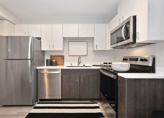 a kitchen with stainless steel appliances and white cabinets  at Track 281 Apartments, California