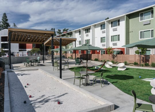 a courtyard with tables and umbrellas in front of an apartment building