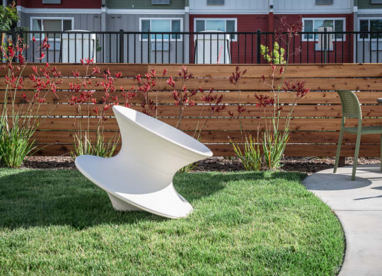 a white urinal sitting in the grass next to a chair