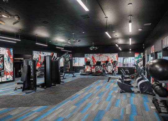 a fitness room with weights and other exercise equipment and a wall of graffiti
