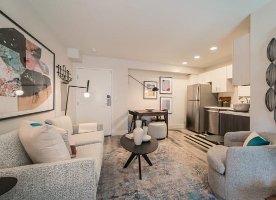 a living room with couches and chairs and a table in front of a kitchen