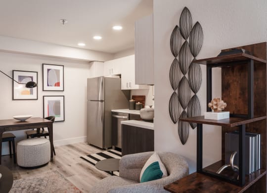 a living room with a couch and a table and a kitchen with a refrigerator
