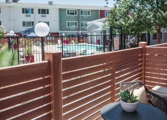 a patio with two chairs and a table on a balcony  overlooking the pool area at Track 281 Apartments, Sacramento, 95811