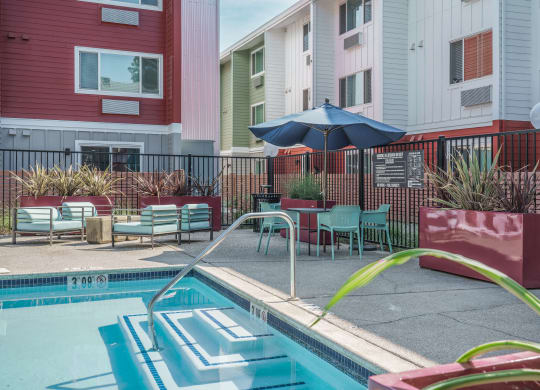 our apartments have a pool and a patio with chairs and an umbrella