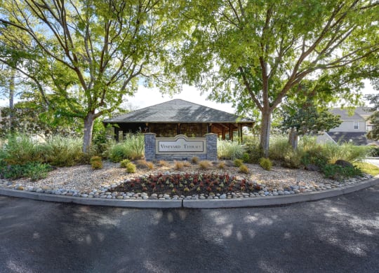 Vineyard Terrace community entrance with monument signage and mature trees on each side at Vineyard Terrace Apartments, Napa, California