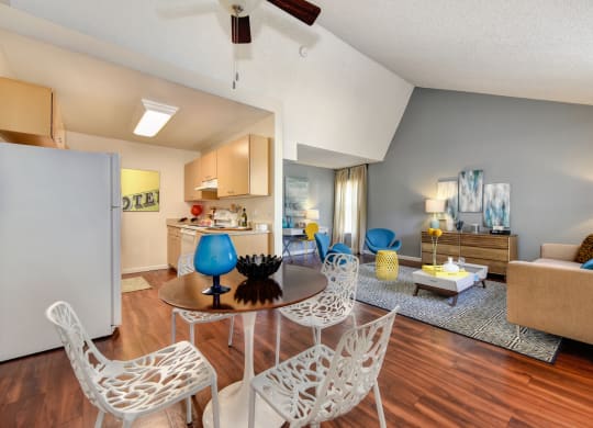Living Room with View of Kitchen with Hardwood Inspired Floor, White Sofa, Rug and Blue Chairs at Vineyard Terrace Apartments, Napa
