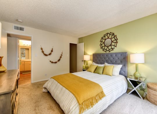 Bedroom with Carpet, light green accent Wall, two nightstands and yellow throw blanket on the bed at Vineyard Terrace Apartments, Napa, CA