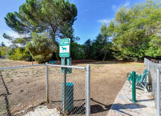 Community gated dog park with pet waste station at entrance and bench inside the fenced area at Vineyard Terrace Apartments, Napa, California