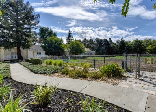 Community dog park/dog run which is fenced in with pedestrian walkway outside the park area at Vineyard Terrace Apartments, Napa, CA, 94558