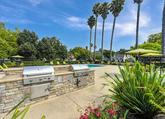 A backyard with a stone wall and a grill at Vineyard Terrace Apartments, California
