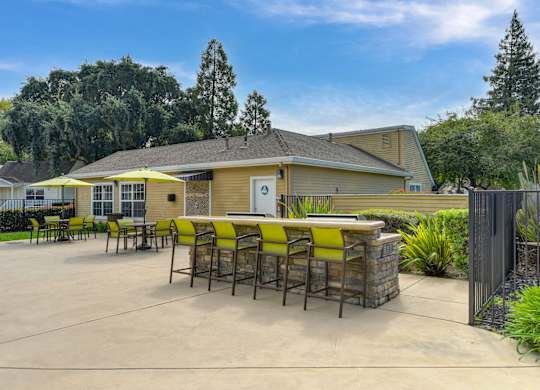A yellow and brown building with a patio and chairs at Vineyard Terrace Apartments, California