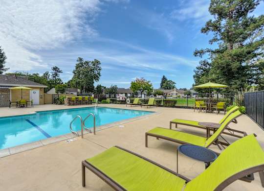 A pool area with sun loungers and a yellow umbrella at Vineyard Terrace Apartments, California