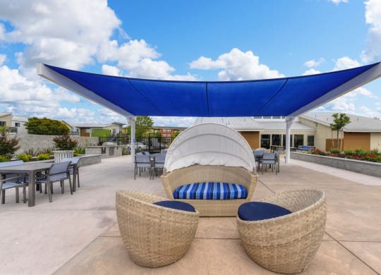 Outdoor Lounge with Wicker Chair, Blue Sun Cover, Tables and Chairs, Blue Sky with Clouds at Addison Ranch Apartments, Petaluma, California