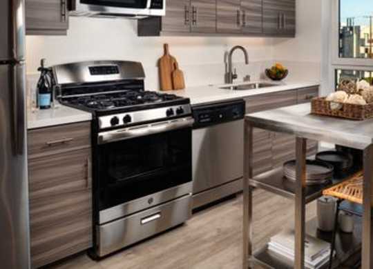 A modern kitchen with stainless steel appliances and wooden cabinets.