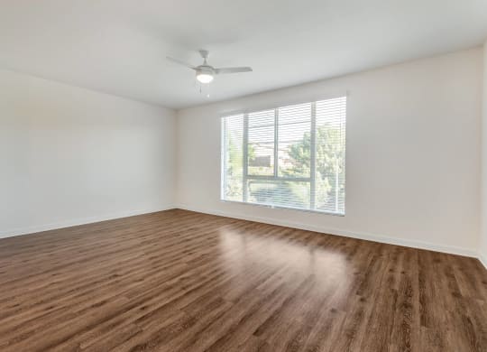 an empty living room with a window and wood flooring
