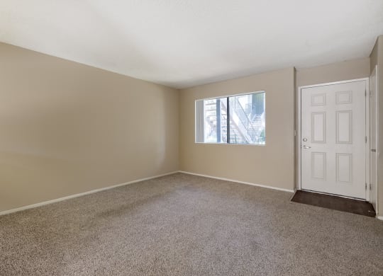 an empty living room with carpet and a white door