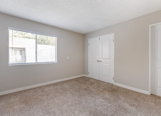 an empty bedroom with white doors and a window