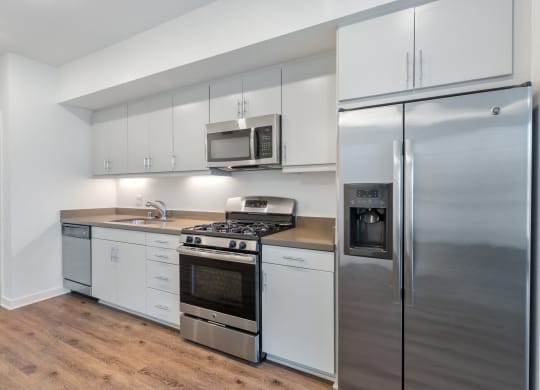 a kitchen with white cabinets and stainless steel appliances and a refrigerator