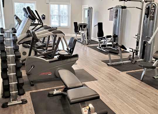 A gym with a variety of equipment including treadmills, weights, and a bench press.
