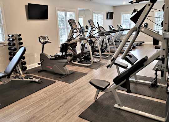 A gym with treadmills, exercise bikes, and weight racks.