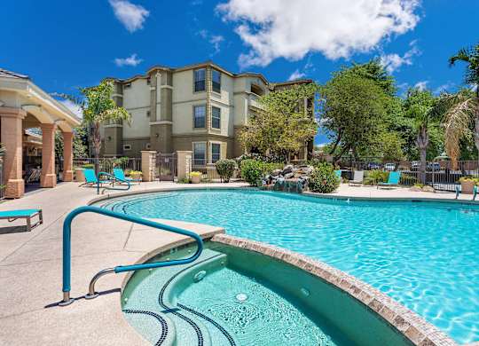 A swimming pool in front of a building with a blue sky in the background. at Superstition Canyon Apartments, Mesa, Arizona