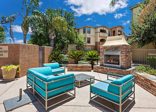 A patio with a fireplace and two chairs. at Superstition Canyon Apartments, Apartments, Mesa, AZ