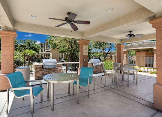 A patio with a table and chairs under a roof. at Superstition Canyon Apartments, Apartments, Mesa, AZ