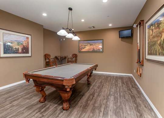 A pool table in a room with brown walls and wooden flooring. at Superstition Canyon Apartments, Arizona